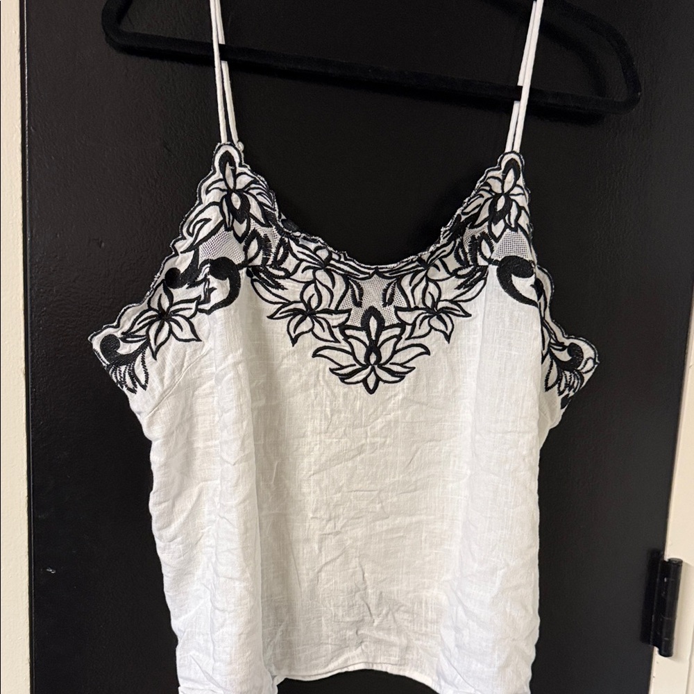 Express white camisole featuring intricate black floral embroidery.